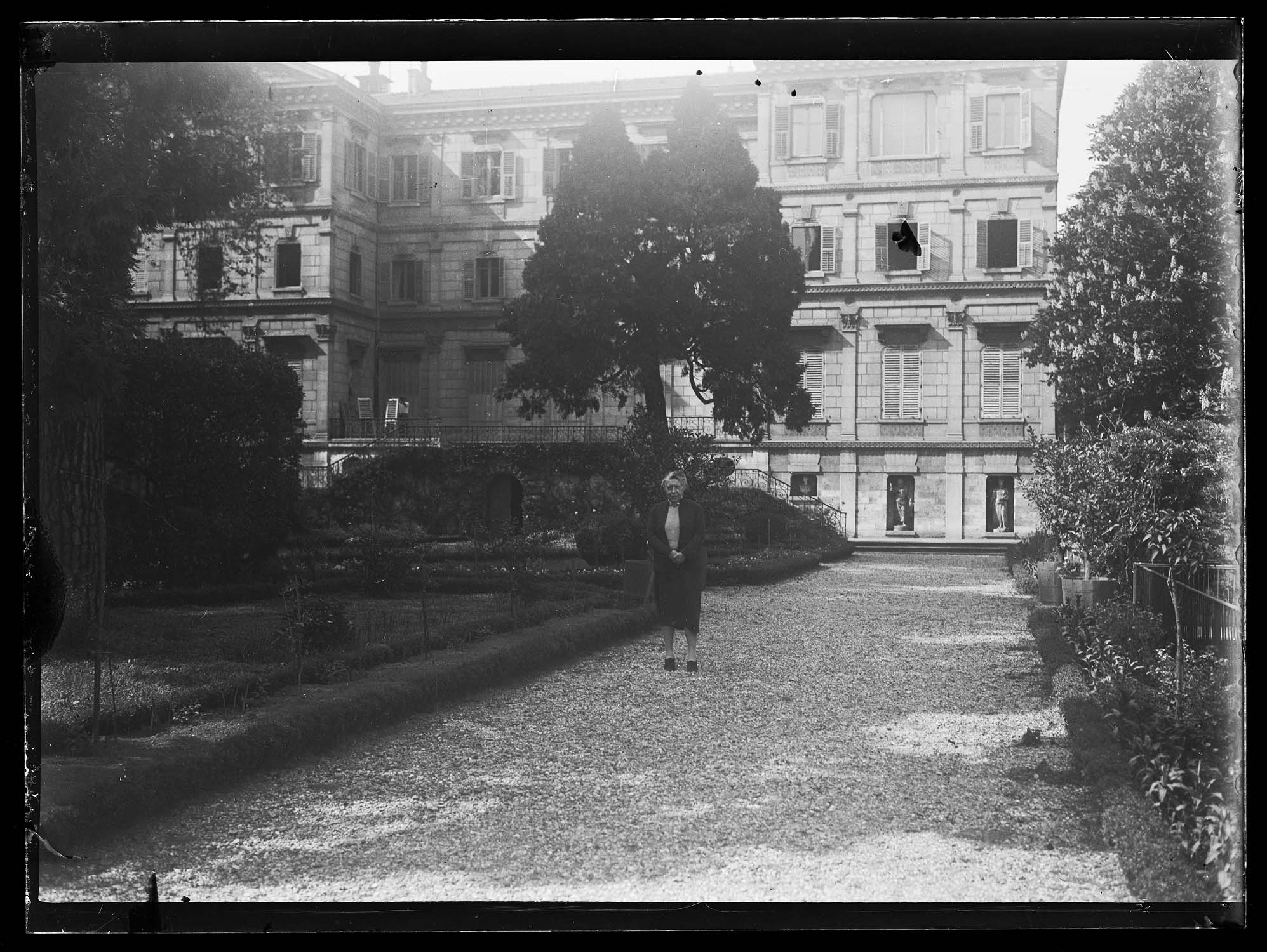 Une femme dans le jardin, avec le bâtiment à l'arrière-plan